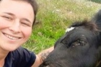 Female wildlife warden looking at the camera next to a cow