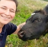 Female wildlife warden looking at the camera next to a cow